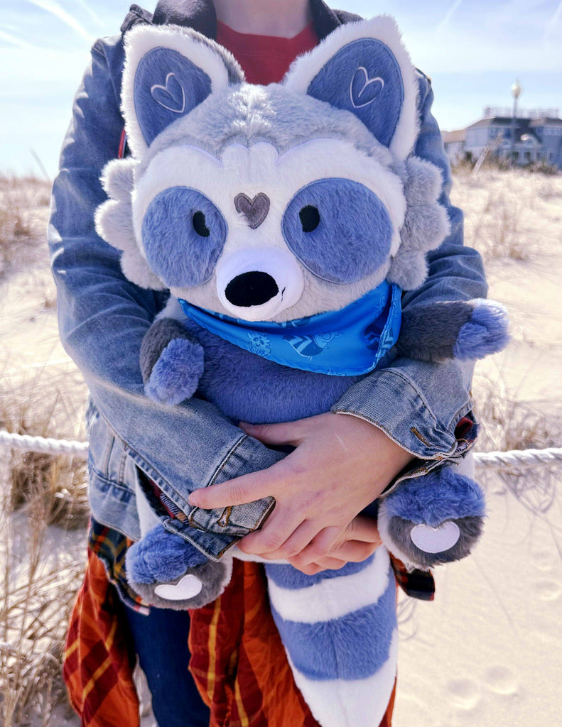 Person holding a plush backpack of Peanut the blue and grey raccoon