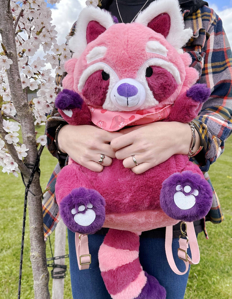 Person holding a plush backpack of Raspberry the red panda