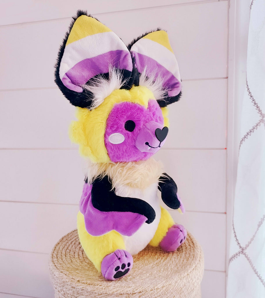 Plush toy of Butter the bat who is yellow, purple, white, and black