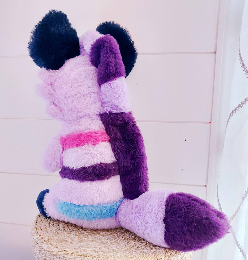 Back view of Berry the Hyena plush who is purple with blue, pink, and dark purple stripes