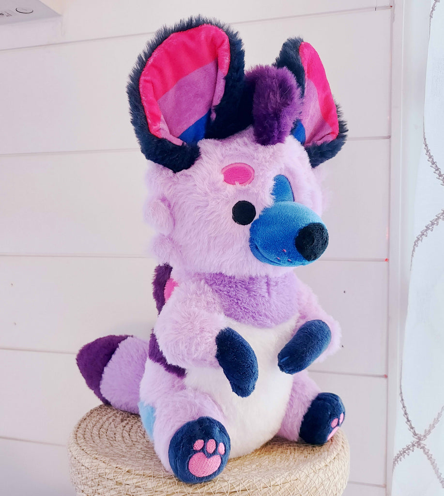 Plush of Berry the Hyena who is purple, blue, and pink