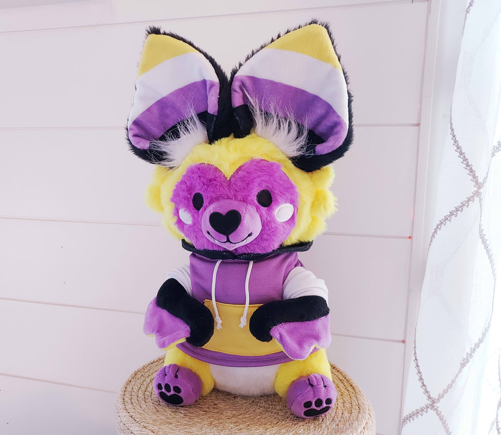 Plush toy of Butter the purple, white, yellow, and black bat wearing a hoodie 
