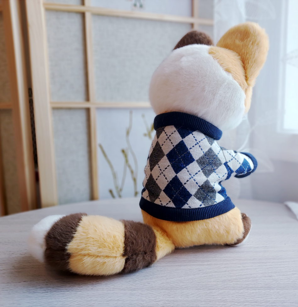 Back view of a plush toy of Doodle the calico cat wearing a  blue argyle sweater