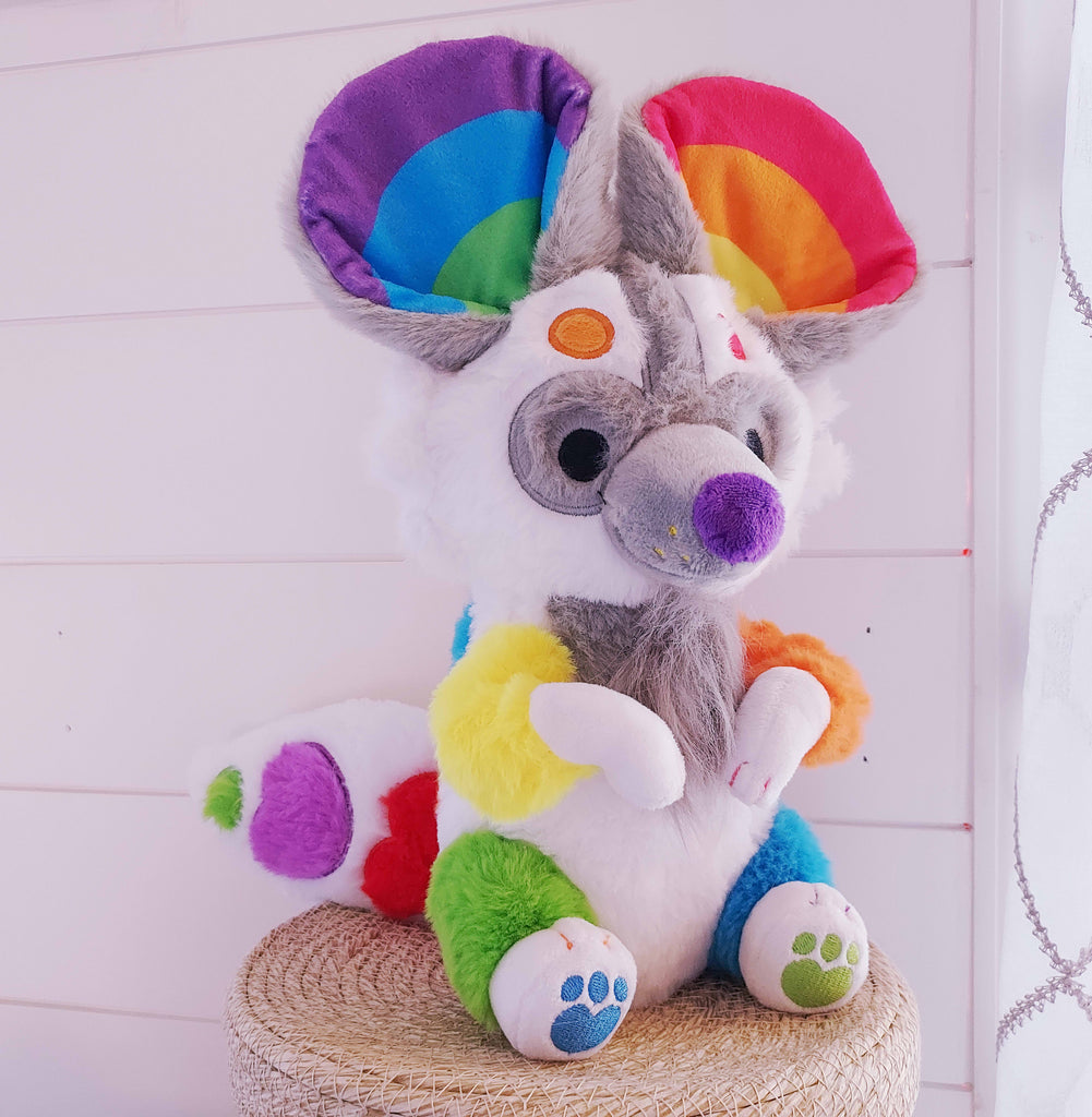 Plush toy of Sprinkles the rainbow painted dog 