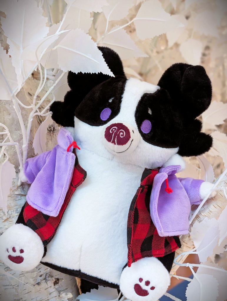 CosyPaws plush of Starry Pup the black and white border collie wearing a purple jacket and sitting in white plants