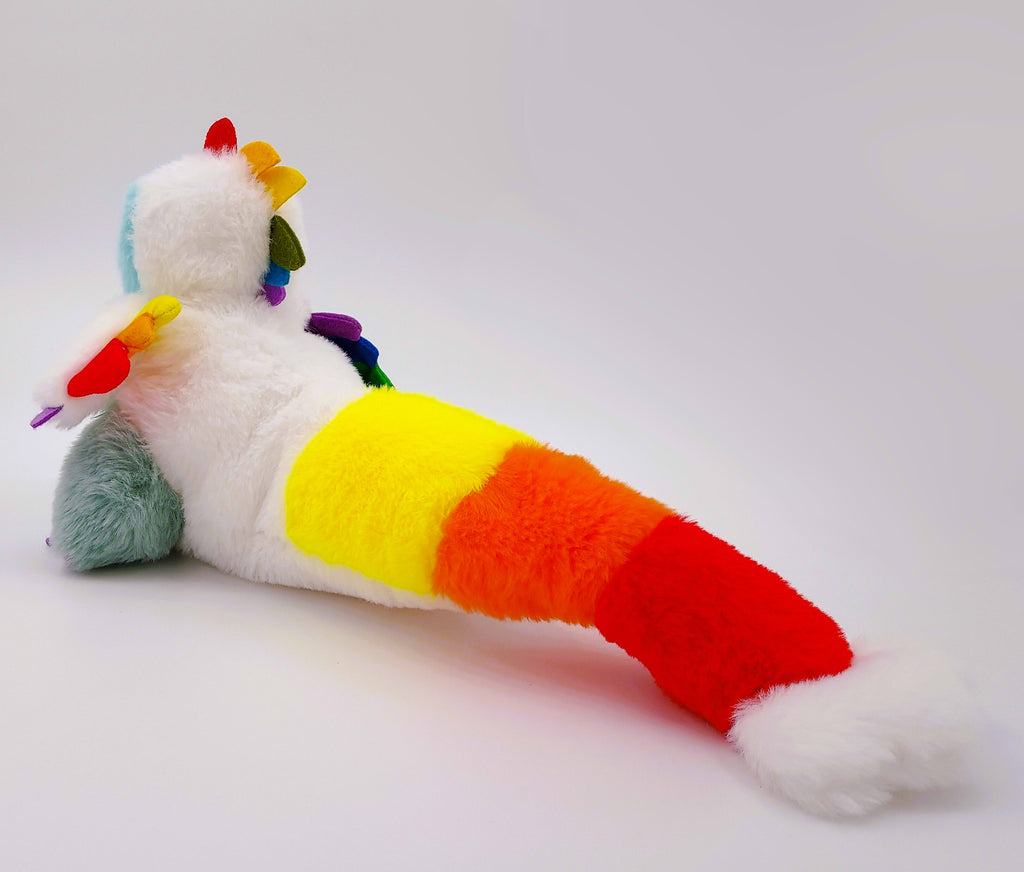 Plush toy of Sugar Cookie the Rainbow Utahraptor dinosaur