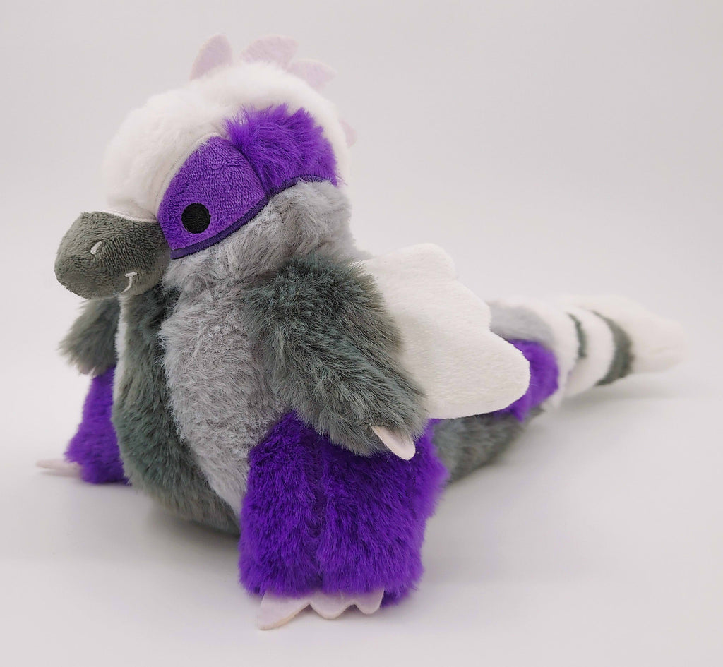 Plush toy of Sugar Plum the black, white, grey, and purple utahraptor