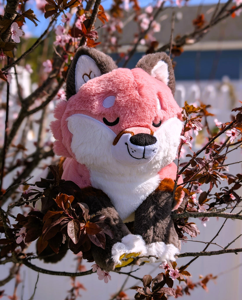 Plush toy of Chiffon the red fox sitting in a flowering tree