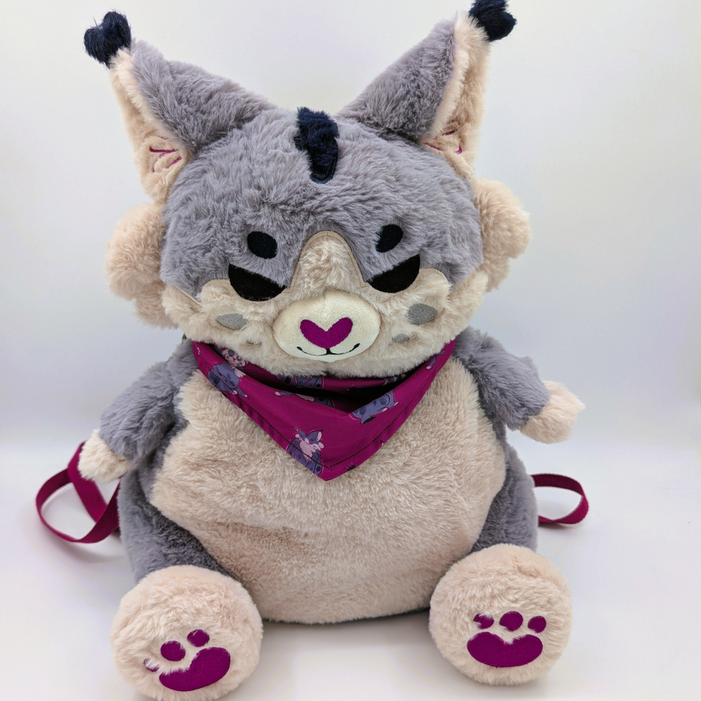 Plush backpack of a grey lynx wearing a aubergine bandana with matching paw pads  