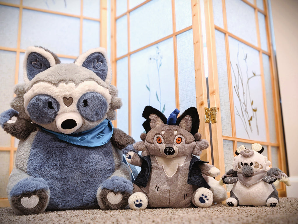 Plush toy of Wolfgang the werewolf between a plush backpack of Peanut the raccoon and BeanBuds plush of Sesame the gryphon