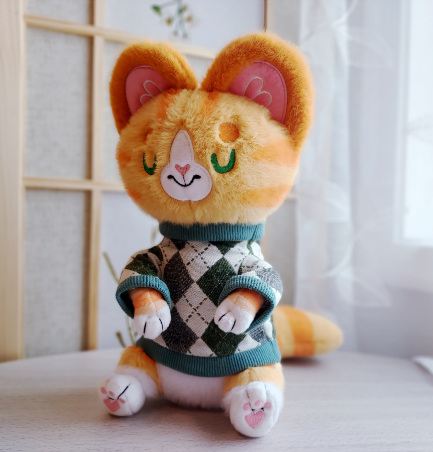 Plush toy of an orange cat in a sweater