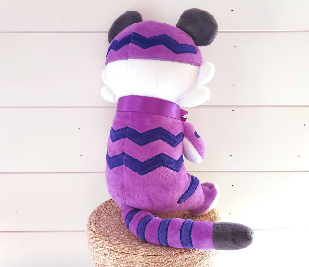 Back view of a plush toy of Lotus the purple tiger wearing a purple bow