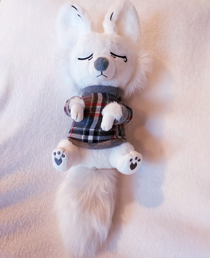 Plush toy of Anxiety Fox, a white fox wearing a grey and red plaid sweater