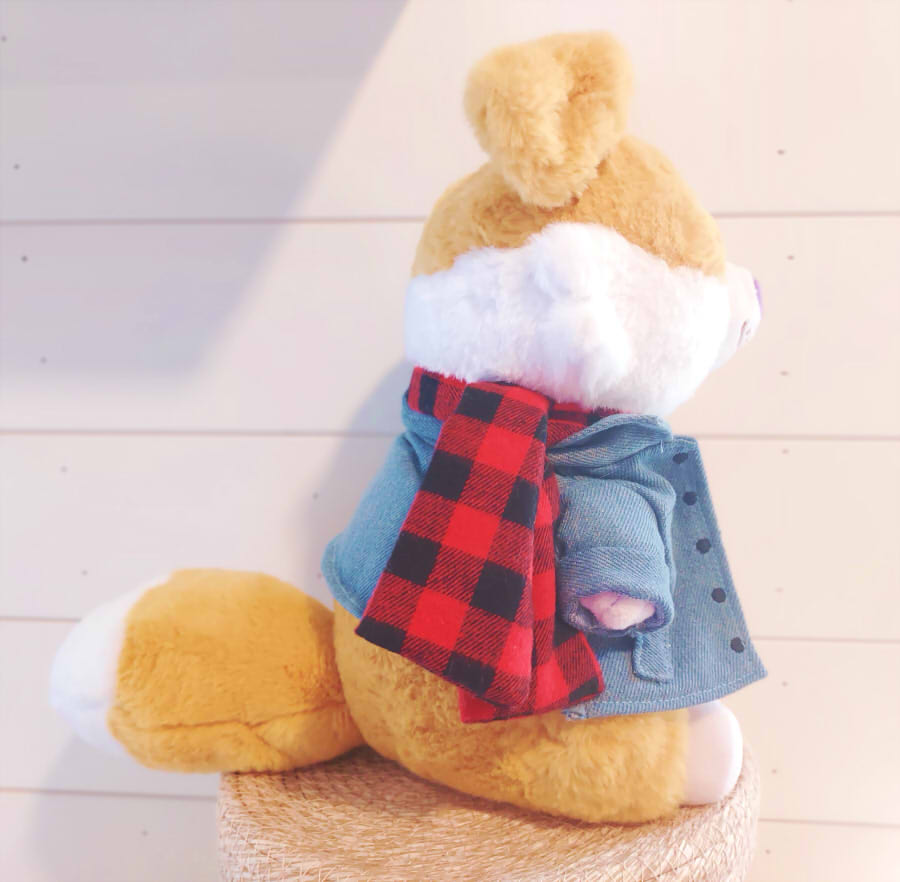 Side view of a plush of Sunny Pup the red border collie wearing a red scarf, Heckfire Pup shirt, and jean jacket